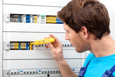 Repairman checking a voltage and fixing a switchboard